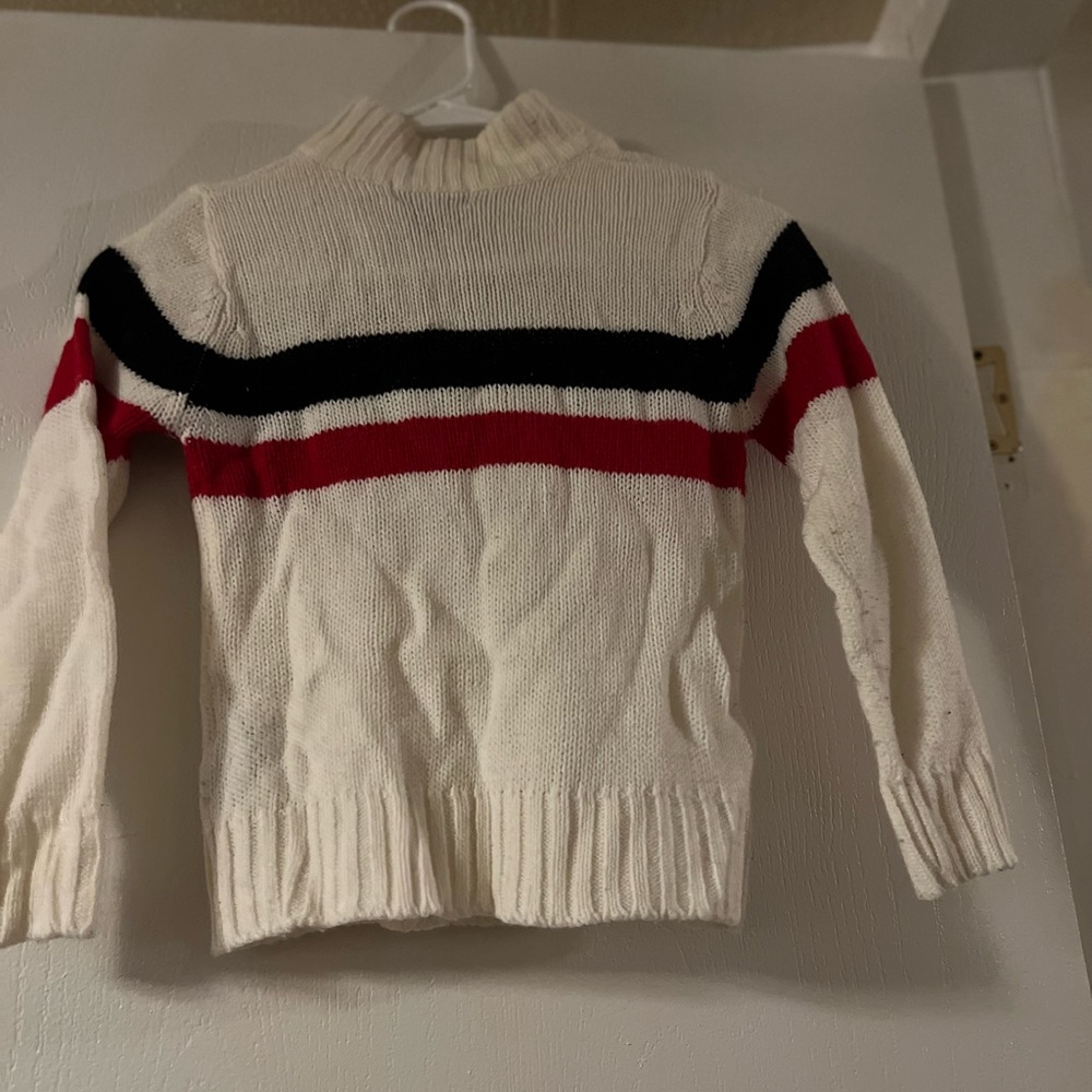 White sweater with red and blue design.